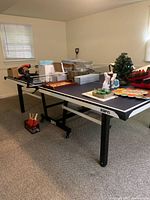 Full view of navy blue ESPN ping-pong table with various items on top not included in sale.