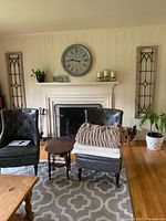 Two identical tall rectangular wall hangings flanking a fireplace, light grey wood frames with black iron scrollwork design, metal corner caps.