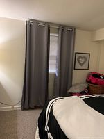 Four gray blackout curtain panels hanging on curtain rods in a bedroom, covering two windows.