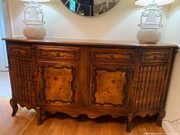 Full view of the sideboard showing the wooden top, decorative central doors, and side cabinets with faux book spines