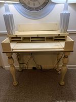 Front view of vintage solid wood desk showing cubby storage and turned legs.