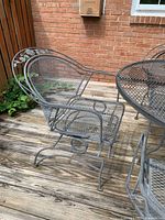 Right-side view of one rocking chair showing mesh seat, scroll arms and coil spring base