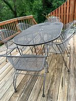 Overall view of oval wrought iron patio table on deck with bench and chairs around