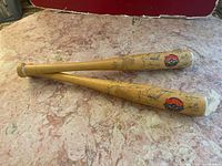 Two wooden miniature baseball bats side by side on a marble surface, showing printed signatures and Blue Jays logo