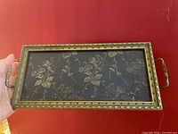 Top view of the rectangular brass and glass tray showing the gold floral pattern under glass.