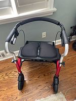 Front view of Evolution Xpresso Lite walker showing padded seat, hand grips, and front wheels.