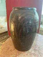 Front and side views of large dark brown glazed pottery vase showing its shape, decorative incised horizontal lines, and glossy finish.