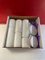 Box set of six white pillar candles and six white ceramic coasters with cork backing. Candles vary in height, coasters wrapped in bubble wrap.