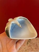 Porcelain trinket dish held in hand showing seagull figure on dish edge and blue interior.