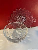 Front angle of two glass items: bubble bowl in front with bubble pattern, handled platter behind with starburst honeycomb geometric pressed glass design