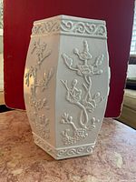 Front side showing raised floral and botanical relief on white hexagonal stool