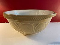 Side view of the ceramic mixing bowl showing the embossed geometric pattern and tan rim.