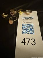 Five gold-tone fashion rings displayed beside lot card