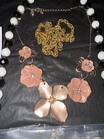 All jewelry pieces laid out including long bead necklace, floral bib necklace, gold chain