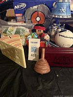 All items grouped: boxed Nerf set, spinning top, Mulan box, rag doll, cheese-wedge box, white stitched ball, blue bell