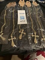 Five identical gold-tone cross necklaces in individual plastic packaging