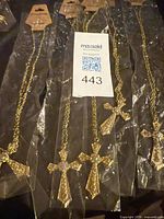 Five gold-tone cross necklaces in packaging
