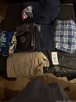 All items laid on table: hoodie, AT&T bag, plaid shorts, beige pants, floral shirt