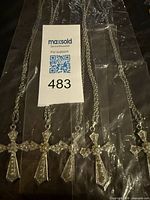 Five silver-tone cross necklaces laid out in plastic sleeves