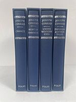 Four blue hardcover Folio Society books by Joseph Conrad in slipcases aligned vertically showing spine titles.