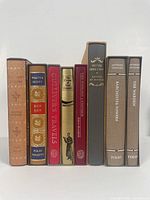 All 8 Folio Society books upright side by side showing spines, titles, and slipcases.