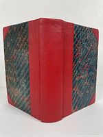 Spine and front cover of one volume showing red leather spine and marbled dark blue and red cover