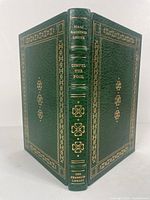 Full view of the book showing green leather binding with gold embossed decorative borders and spine text including author name and title.