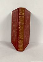 Full view of the spine and front and back covers of the leather bound book showing gold decorative embossing and title.