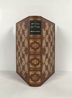 Front and spine of the leather bound book showing title and gold ornate decoration.