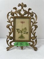 Front view of the ornate antique gilt cast iron Art Nouveau frame holding a floral print illustration against a white background.