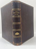 Front and spine view of the leather bound book showing gilt decorations and title "The President's Book" on spine.