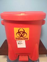 Front view of red biohazard waste bin showing lid and biohazard symbol sticker with biohazard text