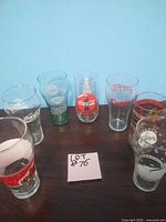 Lot of 7 assorted vintage promotional glasses showing various logos and styles, all in good condition, no chips visible.
