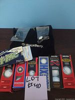 Photo showing BlackBerry branded golf towel, multiple boxes of Top-Flite golf balls (Max Distance, Super Long, Infinity), and golf tees.