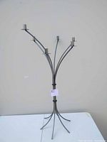Full view of the metal candelabra showing its five arms and candle holders with curved structure and base.