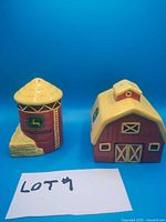 Front view of John Deere barn and silo salt and pepper shakers with lot identification card.