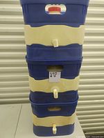Stack of three large blue and beige plastic water containers each with a front white spigot and handles at top and sides.