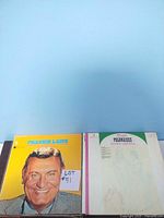 Two vinyl record albums visible: one featuring Lawrence Welk on the cover, and another showing sheet music for Chopin's Polonaise. White background with folder holding the records.