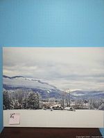 Full view of the winter farm house scene painting with snow-covered trees and mountains