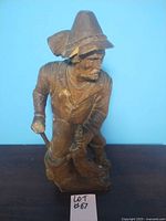Front view of the 20-inch tall wooden trapper statue showing carved details and the figure in a crouched position with tools.
