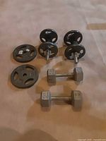 Photo of various hand weights including fixed dumbbells and adjustable plates with collar screws.