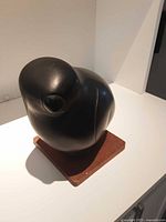 Front left angle view of the Inuit bird carving on a wooden base showing rounded head and smooth finish.