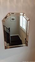 Front view of large octagonal mirror mounted on a wall, showing the gold frame and reflections.