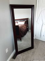 Front view of the large vertical mirror showing the red cherry wood frame and reflective surface.