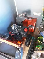 Side view of orange Noma snowblower showing engine, chute and tire.