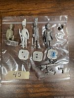 Photo of assorted vintage metal miniatures including painted and unpainted soldiers, a horse with a blue saddle, and loose accessory parts.