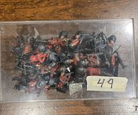 Overhead view of vintage metal Britains miniature British Royal Guard soldiers housed in a clear plastic box showing condition and quantity.