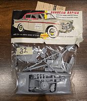 Photo of Airfix Sunbeam Rapier 1/32 scale plastic model kit in original packaging with parts visible inside clear bag portion. Includes illustrated packaging showing car image and kit details.