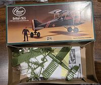 Opened box showing green plastic model parts on sprues along with instruction sheet inside the box.
