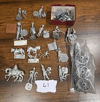 Rose metal military miniatures laid out showing multiple soldier figures, horses, and artillery wheels.